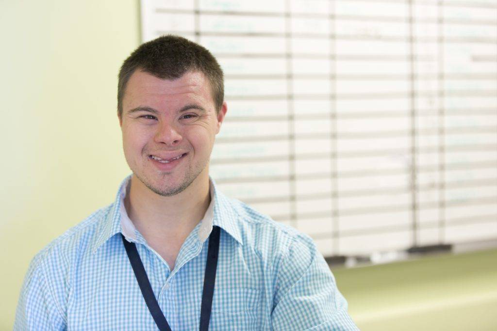 Caucasian man with Down Syndrome smiling in office | ResCare - ResCare