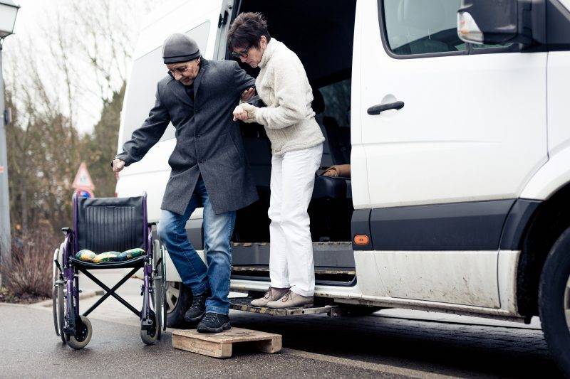 caregiver helping man out of van