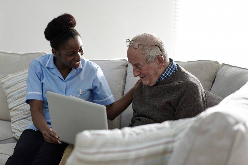 caregiver helping man with a laptop